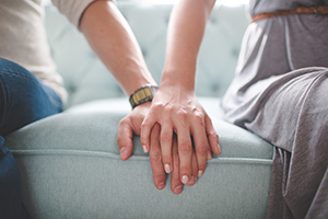 Two people holding hands while sitting on a couch