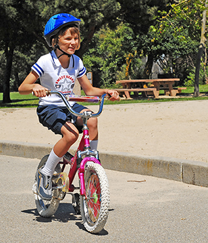 Girl riding bicycle, wearing helmet.